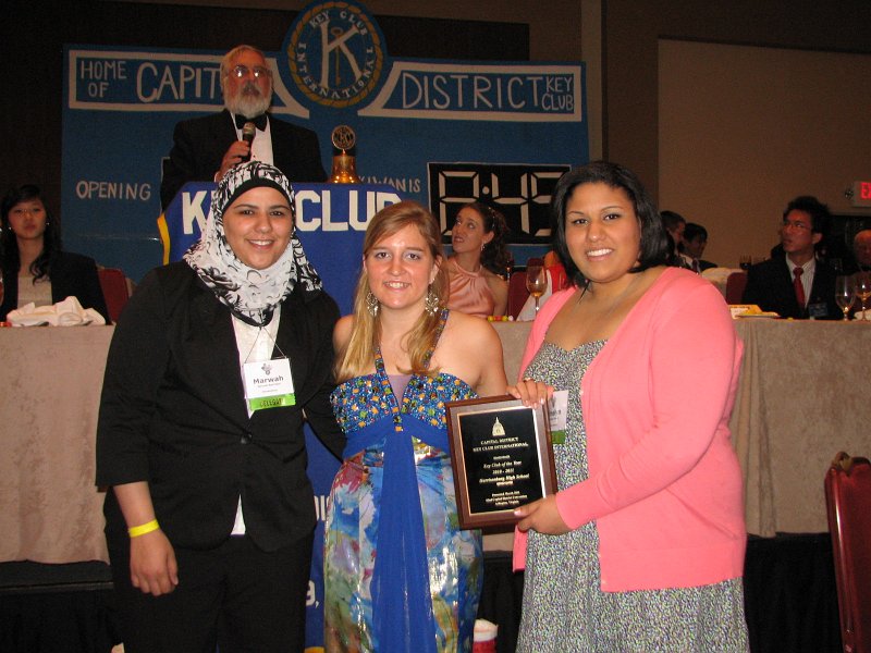 IMG_0820.JPG - On Sunday morning at the Farewell Session Breakfast and as a part of the Year’s Special Awards, outstanding club and individual attainment is recognized.  The District’s Key Club of the Year is awarded to the Harrisonburg High School Key Club, Virginia.  Accepting the club’s award from Governor Rachael is Marwah Bani Hani, Distinguished Club Vice President. Key Club Administrator is announcing the awards as Governor Rachael presents the plaques.