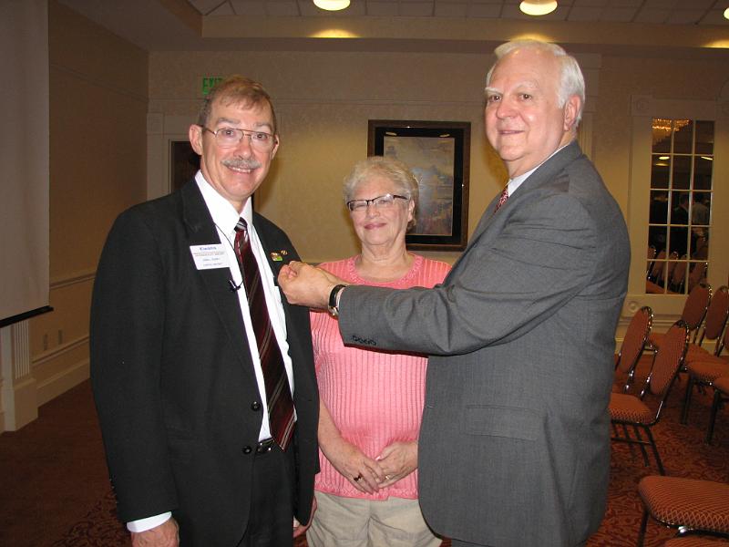 IMG_0233.JPG - KI Trustee Jerry Peuler pins Gov. Designate Don Dudey and Don's wife, Jan, looks on.